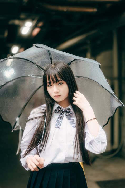 A Girl In A School Uniform Holding An Umbrella And Posing For The