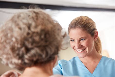 Caring Geriatric Nurse Cares For Elderly Woman In Rehab Or Nursi