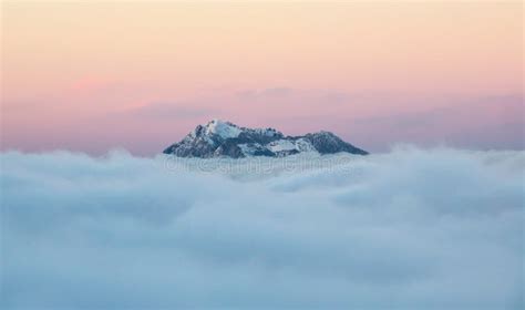 Single Mountain Peak Above The Clouds Under A Colorful Morning Sky