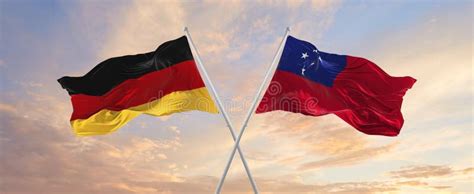 Flags Of Germany And Samoa Waving In The Wind On Flagpoles Against Sky