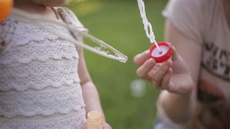 mother and daughter blowing bubbles outdoors in summer sunshine stock video footage 00 13 sbv