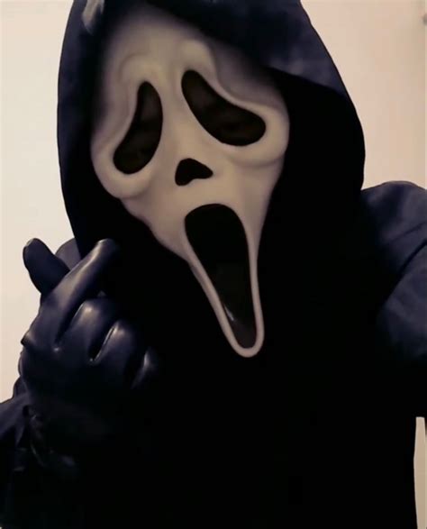 A Person In A Black Hooded Jacket With A Ghost Mask On And Mouth Wide Open