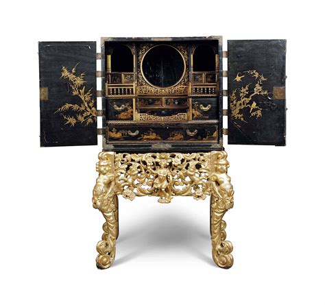 Chinese black lacquer furniture and cabinets with intricate hand painted gold leaf designs depicting chinese cranes within beautiful sunset scenery. A CHINESE GILT-METAL MOUNTED BLACK LACQUER CABINET-ON-STAND