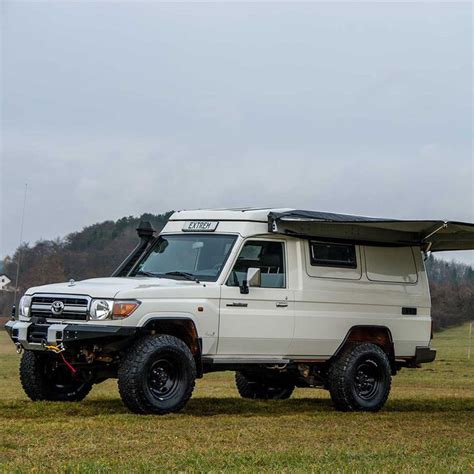 An Off Road Vehicle With A Camper Attached To The Roof Is Parked In A Field