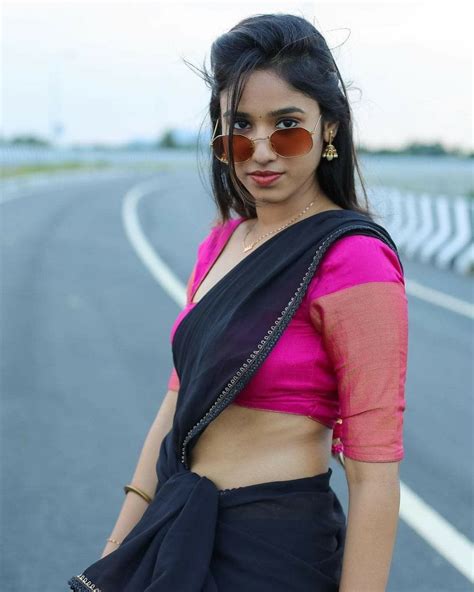 A Woman In A Pink Top And Black Skirt Standing On The Side Of A Road