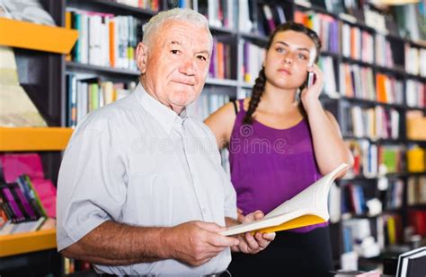 Old Man Is Choosing Book While Girl Chatting By Phone In Bookstore