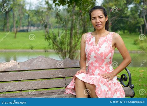 Happy Mature Asian Woman Relaxing At The Park Outdoors Stock Photo