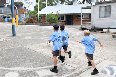 Three School Boys Playing In School Yard With Football Stock Photo