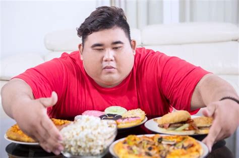 Premium Photo Greedy Fat Man Hugging At A Lot Of Unhealthy Food