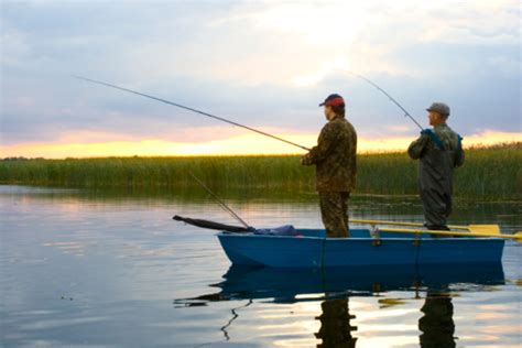 Two Fishermen With Fishing Rods In Small Boat Stock Photo Download