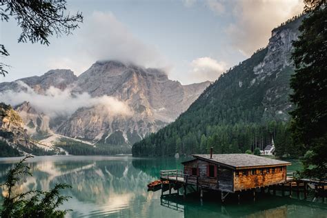 A Log Cabin Lakehouse And Dock On Lago Di Braies With The Snow Capped