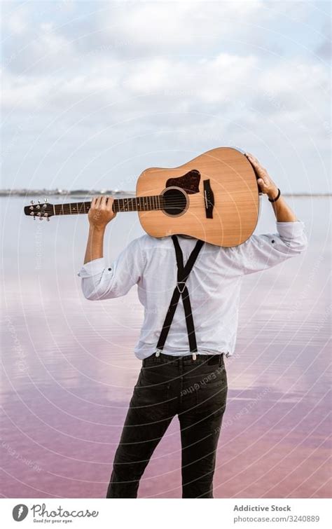 Musician Gazing And Carrying Guitar Behind Back While Standing On Beach