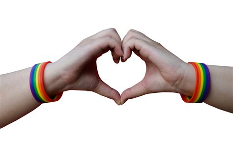 close up of male hands with gay pride rainbow awareness wristbands showing heart gesture with