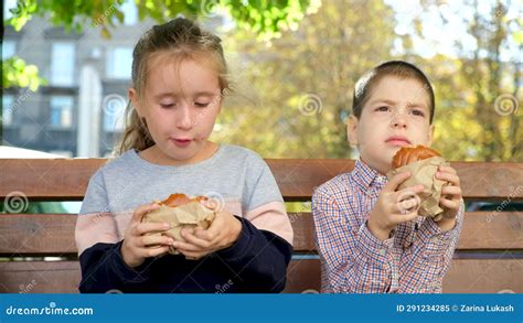 Small Children A Boy And A Girl Eat Burgers Street Food Sitting On A