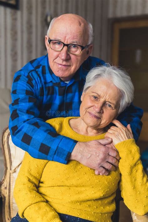 Portrait Of An Elderly Couple Caring Husband Standing Behind His Happy Loving Wife And Hugging