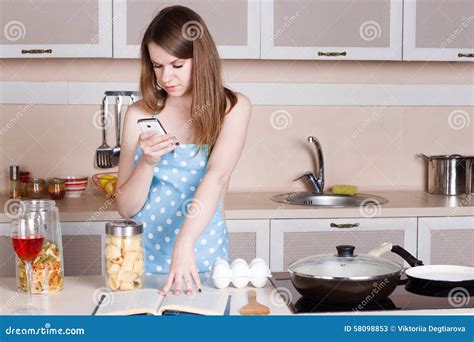 la fille dans la cuisine portant un tablier au dessus de son corps nu prépare et examine le