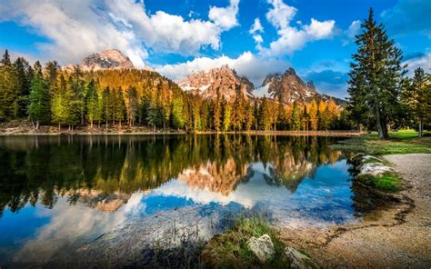 Dolomites In Italy Rocky Mountains With Snow Pine Forest Sky With White Cloud Reflection In A