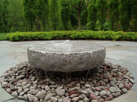 A Stone Fountain Surrounded By Rocks And Gravel