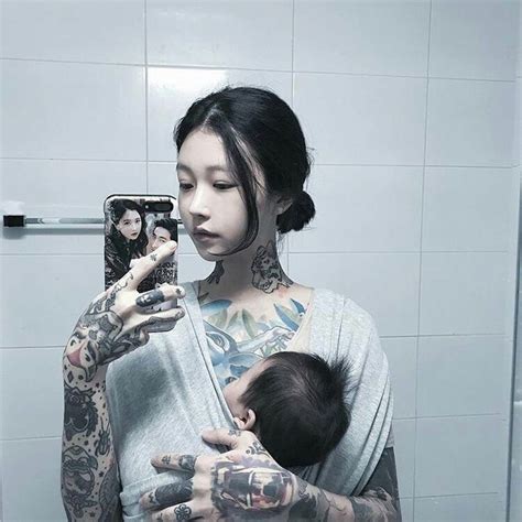 A Woman With Tattoos Holding A Baby In Her Arms