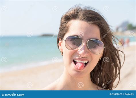 Счастливая молодая женщина вставляя вне язык на пляже Стоковое Фото изображение насчитывающей