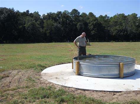 A Man Standing In Front Of A Large Metal Barrel On Top Of A Grass