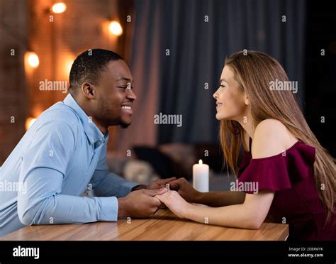 Romantic Date Loving Interracial Couple Sitting At Table In Restaurant