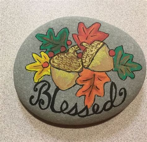 A Painted Rock That Says Blessed With Leaves And Acorns On The Side
