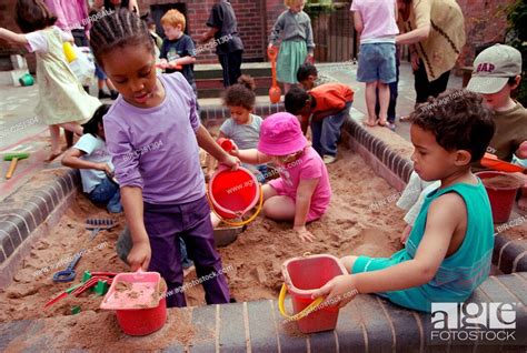 Multiracial Group Of Nursery School Children Using Buckets And Spades