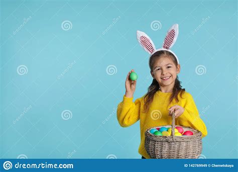 Little Girl In Bunny Ears Headband Holding Basket With Easter Eggs On