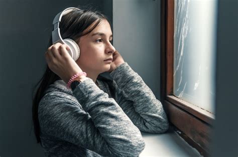 Contenido variado pero principalmente triste. Triste adolescente sentado en el alféizar de la ventana con auriculares escuchando música | Foto ...