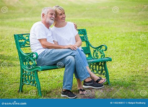 Happy Senior Loving Couple Relaxing At Park Embracing Together In