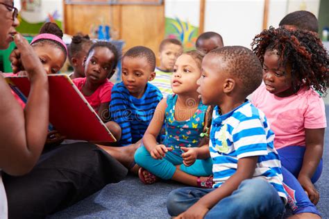 Teacher Reading A Book With A Class Of Preschool Children Stock Photo