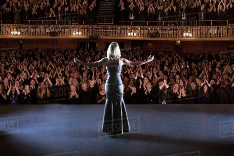 Performer Standing With Arms Outstretched On Stage In Theater Stock