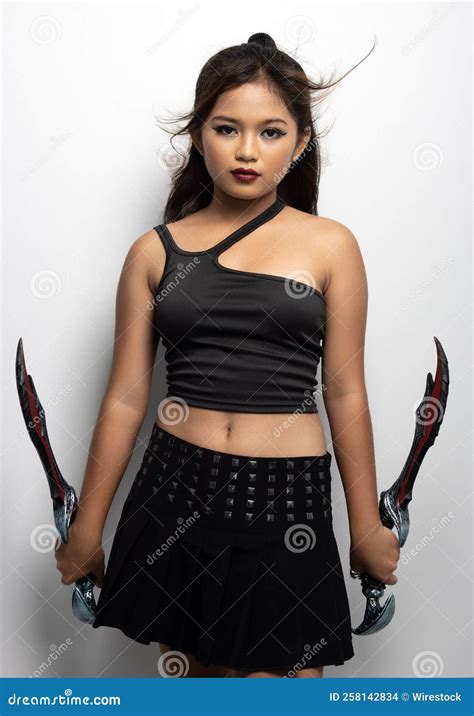 southeast asian girl in a black top and skirt with two fantasy knives