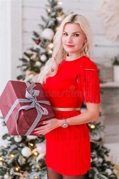 Beautiful Blonde Girl With A New Year`s T In Hands Near The Christmas Tree Stock Image