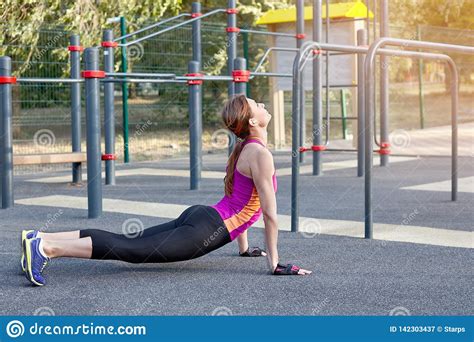 Gorgeous Slim Young Woman Practices Yoga At Outdoor Sportsground Cobra