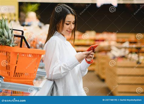 Smiling Young Woman Using Mobile Phone While Shopping In Shopping Store