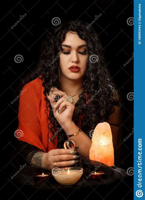 girl gypsy fortune teller with a red handkerchief at the table with nasty cards candles against