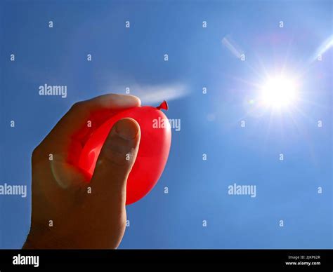 Hand Holds Red Water Balloon Against The Summer Sun Water Bomb Ready