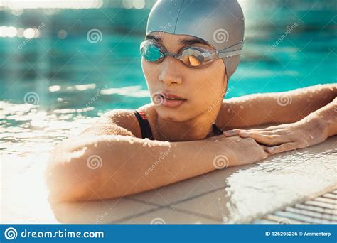 Female Swimmer Relaxing At The Edge Of A Swimming Pool Stock Photo
