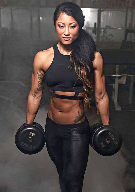 A Woman In Black Top And Leggings With Dumbbells On Her Chest