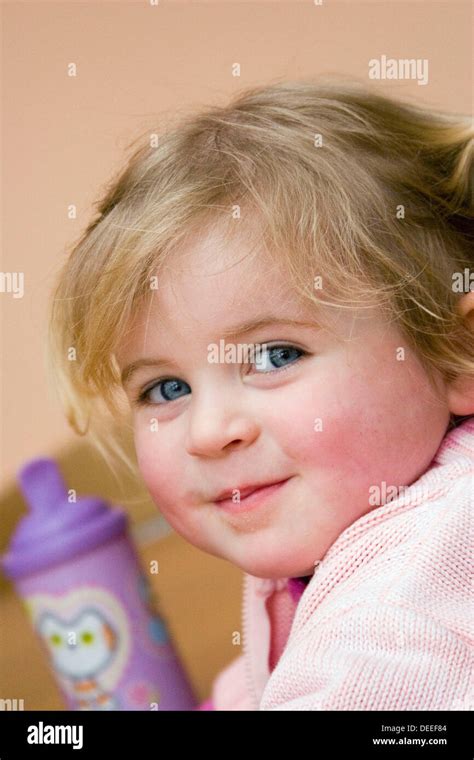 Headshot Of A 3 Year Old Girl Smiling Into Camera Cheekily Stock Photo