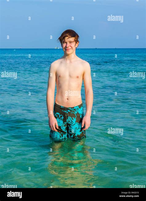 Young Boy Is Standing In The Beautiful Clear Sea And Enjoys The Ocean