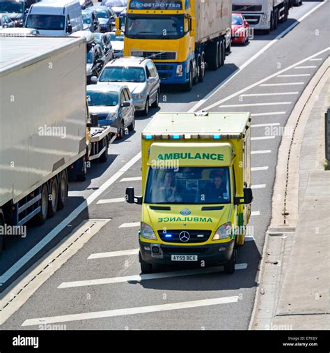 emergency ambulance using motorway hard shoulder to reach accident location at front of