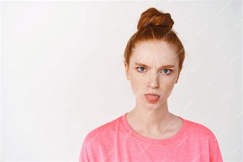 Free Photo Close Up Of Silly Redhead Teen Girl Showing Tongue And Frowning Standing Against