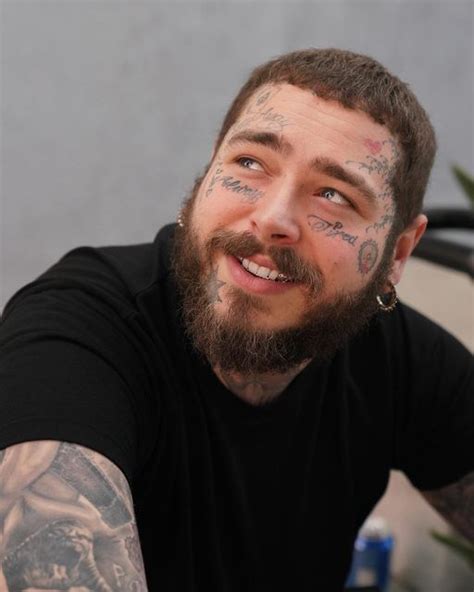 A Man With Tattoos And Piercings On His Face Smiles At The Camera While