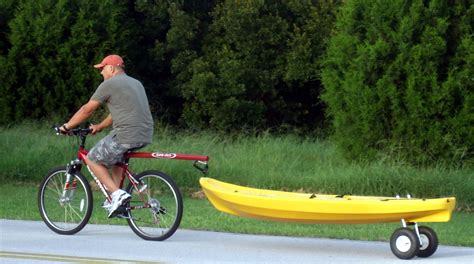 A Man Riding A Bike Next To A Yellow Kayak