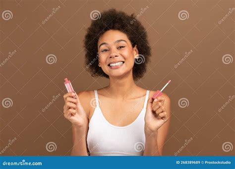 Smiling Pretty Millennial Multiethnic Lady With Nude Makeup Holding Brush And Lip Gloss Stock