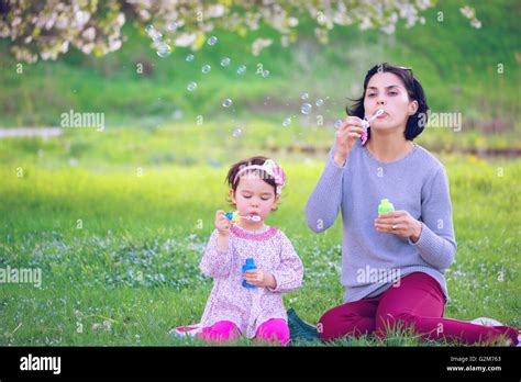 Feliz Joven Madre Y Su Hija Soplando Burbujas De Jabón En El Parque