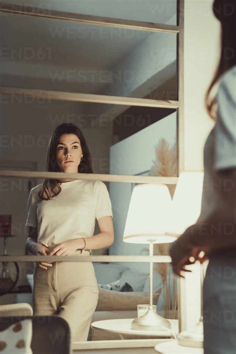 Woman Looking At Her Reflection In Mirror At Home Stock Photo